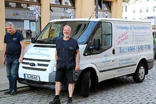 Zwei Monteure stehen seitlich vor einem Firmenfahrzeug Zwei Monteure stehen seitlich vor einem Firmenfahrzeug